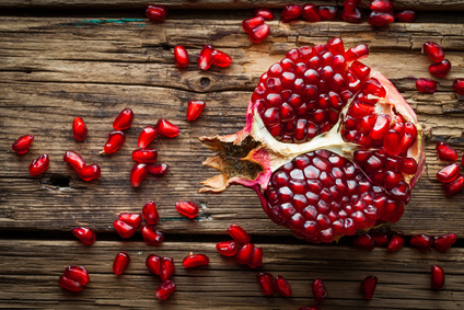 Juicy pomegranate fruit over wooden table Pomegranate Seed Botanical Oil